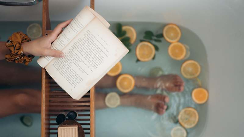 Minimalist flat-lay of lavender-scented bath salts, a ceramic mug with dried chamomile, folded ivory towel, and soft natural light