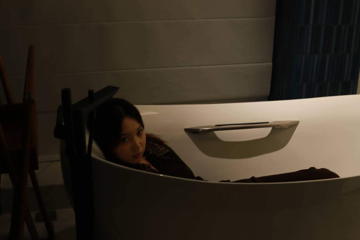 bath bombs for women relaxing floating in a minimalist white bathtub with eucalyptus leaves and soft natural lighting